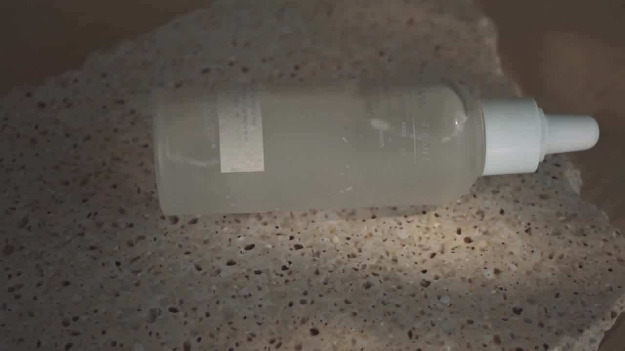 Luma Ray 3.2 AI video example: A cinematic studio product shot of a frosted skincare bottle on pale stone, soft morning light, slow push...