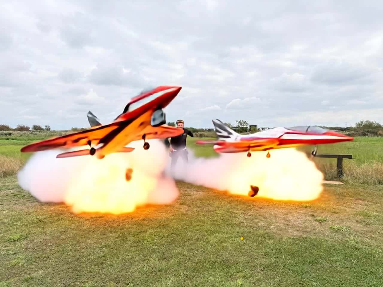 Ejemplo de video IA de Pika 2.2 Image to Video: the jets start to hover and flames come out, the 2 men look shocked and scared and start...