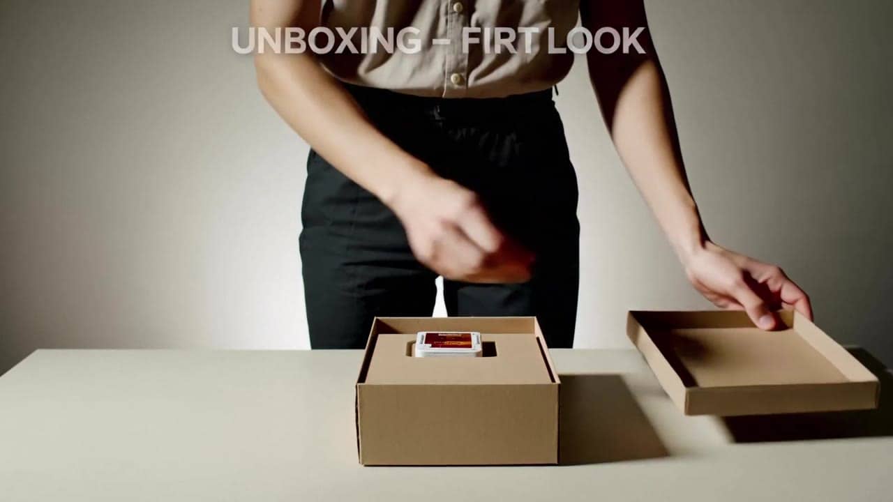 Ejemplo de video IA de LTX 2.3 Fast: Wide 16:9 full-body unboxing video in a clean studio/kitchen setting. A person is fully visible (hea...