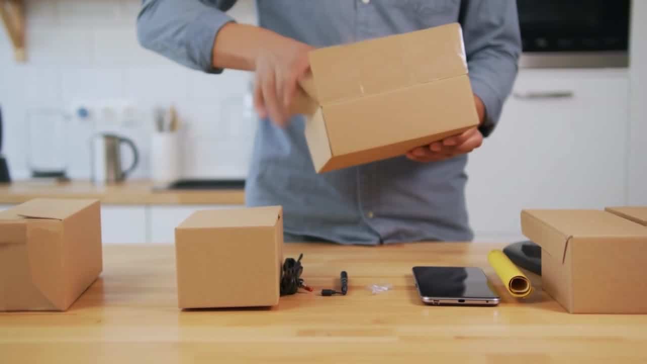 Luma Ray 2 Flash AI video example: Wide 16:9 full-body unboxing video in a clean studio/kitchen setting. A person is fully visible (head...