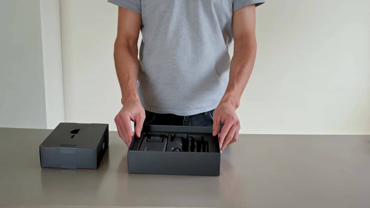 Kling 3 Pro AI video example: Wide 16:9 full-body unboxing video in a clean studio/kitchen setting. A person is fully visible (head-to-to...