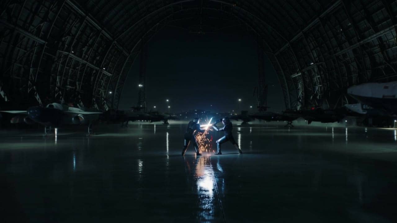 Kling 2.6 Pro AI video example: 10-second 16:9 cinematic shot in a futuristic hangar at night. Two armored fighters stand on a wet metal...