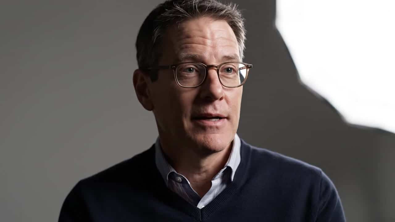 Google Veo 3.1 Fast AI video example: Close-up interview shot. A middle-aged man sits in a minimal studio with soft diffused lighting. St...