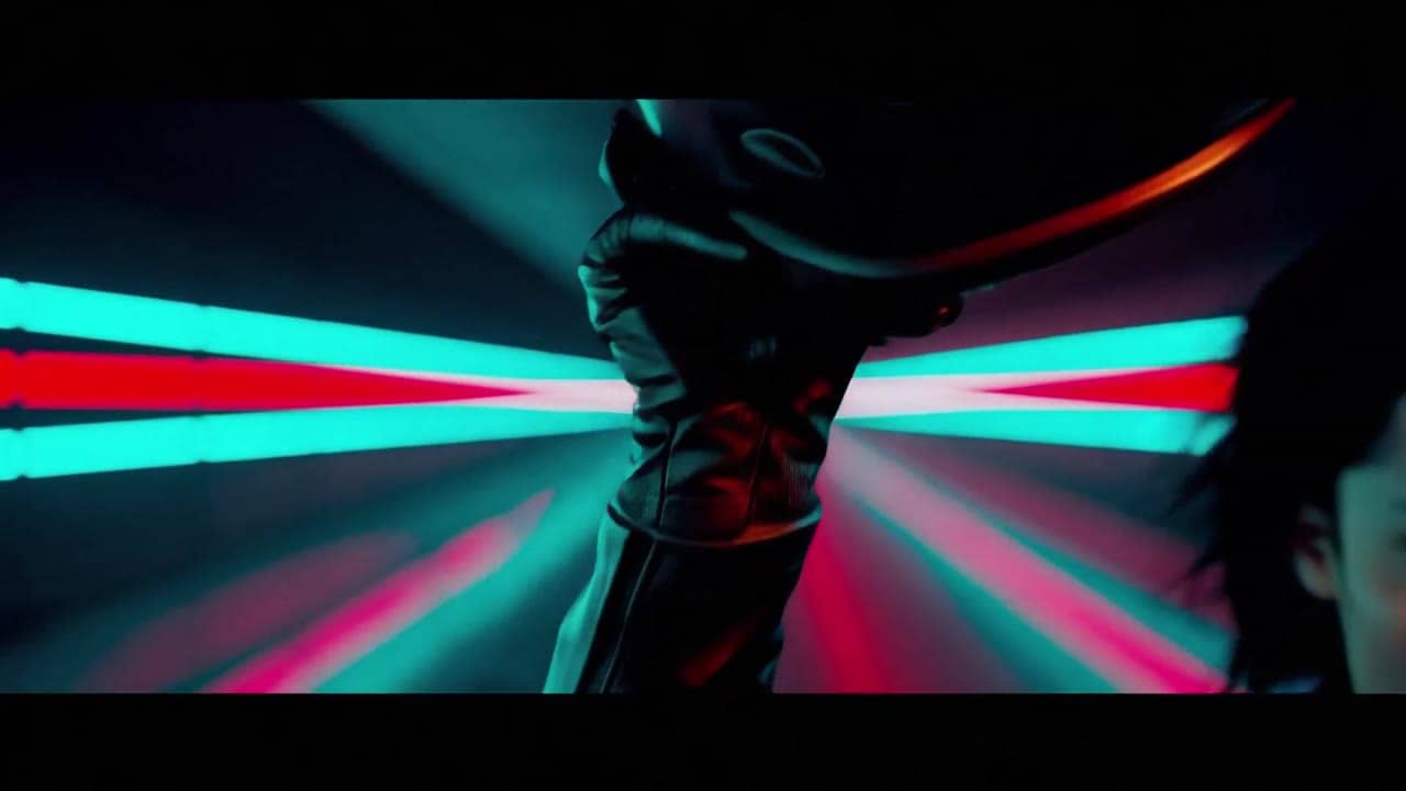 Ejemplo de video IA de LTX 2.3 Fast: A charismatic female racer in a black leather suit stands beside a futuristic motorcycle in a dark n...