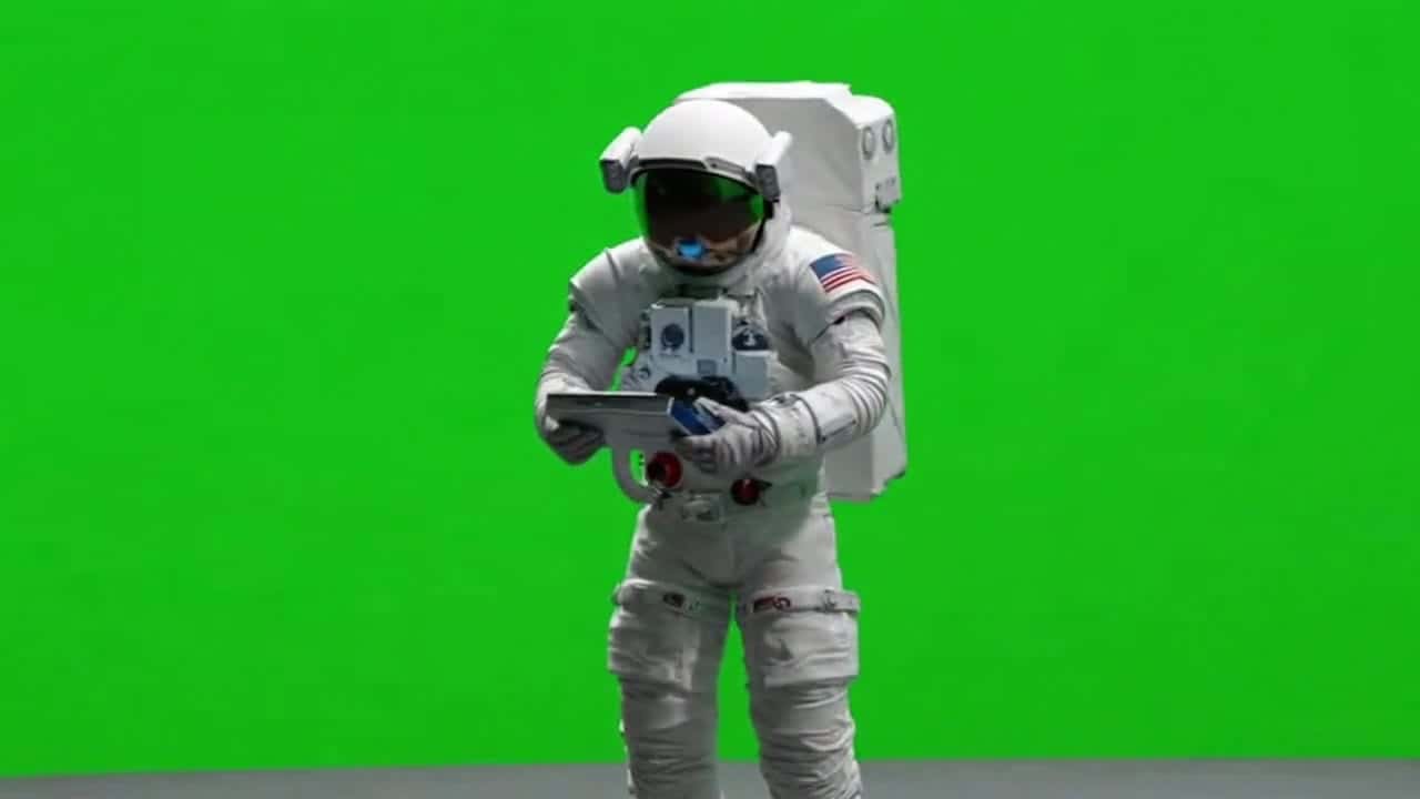 Ejemplo de video IA de OpenAI Sora 2: green screen astronaut standing, examining an instrument and looks on.